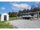 Exterior view shows home with matching outbuilding, gravel driveway, and wooded surroundings at 12160 W Baker Hollow Rd, Columbus, IN 47201