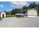 View of home with storage building, gravel drive and wooded landscape at 12160 W Baker Hollow Rd, Columbus, IN 47201