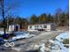 Tan mobile home with deck and storage building, snowy driveway and woods at 12160 W Baker Hollow Rd, Columbus, IN 47201