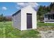Exterior storage outbuilding with white siding, a black door, and single window at 12160 W Baker Hollow Rd, Columbus, IN 47201
