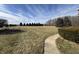 A sidewalk leads through a vast lawn with trimmed trees in the distance on a partly cloudy day at 21989 Schulley Rd, Cicero, IN 46034