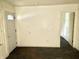 A view of the living room showcasing a plain white door, blank walls, and dark floors at 817 N Linwood Ave, Indianapolis, IN 46201