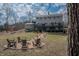 Back of house shows walkout basement with a large wooden deck, a firepit with chairs and treelined backyard at 8850 W State Road 46, Columbus, IN 47201