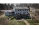 Back of house shows walkout basement with a large wooden deck, a firepit with chairs and treelined backyard at 8850 W State Road 46, Columbus, IN 47201