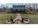 Back of house shows walkout basement with a large wooden deck, a firepit with chairs and treelined backyard at 8850 W State Road 46, Columbus, IN 47201
