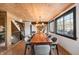 Spacious dining room with a large wooden table, wood ceiling, and natural light at 8850 W State Road 46, Columbus, IN 47201