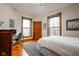 Bright bedroom featuring hardwood floors, two windows, and an adjacent study area with a wooden desk at 1468 Alabama St, Indianapolis, IN 46202