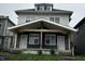 Traditional two-story duplex featuring a shared covered porch, concrete steps, and mixed siding at 2035 Carrollton Ave, Indianapolis, IN 46202