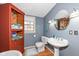 Small bathroom with a pedestal sink, toilet, and wooden storage cabinet at 5202 Woodside Dr, Indianapolis, IN 46228