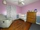 Bedroom with hardwood floors, crib, and rocking chair at 4905 W Southern Ave, Indianapolis, IN 46241