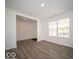 Open living room with wood-look floors, white walls, and a large window overlooking the front yard at 7541 Big Bend Blvd, Camby, IN 46113