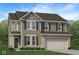 Charming two-story home features a brick-accented garage and covered entry, complemented by lush landscaping at 902 Stonehaven Dr, Indianapolis, IN 46239