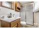 Bathroom with a glass shower, white sink, and wooden cabinetry at 9229 Thrushwood Ln, Indianapolis, IN 46250