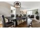 Inviting dining room with modern chandelier, wooden table, bench, and view into a cozy living space at 9229 Thrushwood Ln, Indianapolis, IN 46250