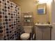 A functional bathroom featuring a toilet, sink, mirror, and shower with curtain at 30 N Muessing St, Indianapolis, IN 46229