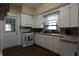 Kitchen featuring white cabinetry, laminate countertops, appliances, and hardwood floors at 30 N Muessing St, Indianapolis, IN 46229