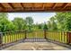Cozy covered wooden deck overlooking the scenic backyard with lush greenery and mature trees at 9600 N 500 E, Pendleton, IN 46064