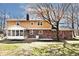 Exterior view of the home featuring a sunroom, patio, brick exterior, and spacious green backyard at 6826 E 65Th St, Indianapolis, IN 46220