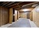 Unfinished basement featuring wood paneled walls, exposed ceiling, and built-in shelving for customizable storage options at 6826 E 65Th St, Indianapolis, IN 46220