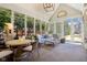 Bright sunroom with large windows, neutral tile floor, and comfortable seating area offers views of the surrounding greenery at 7837 Dean Rd, Indianapolis, IN 46240