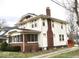 Side view of a traditional two-story home with a brick chimney, small deck, and a partially visible lawn at 917 E 34Th St, Indianapolis, IN 46205