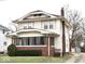 Charming two-story home featuring a brick foundation, enclosed front porch, and a well-maintained lawn at 917 E 34Th St, Indianapolis, IN 46205