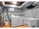Functional basement laundry room with new washer, dryer, utility sink, and orange flooring at 233 W Westfield Blvd, Indianapolis, IN 46208
