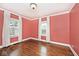 An empty bedroom features salmon colored walls, hardwood floors, and classic windows at 5630 Winthrop Ave, Indianapolis, IN 46220