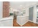 Bright kitchen features an island, stainless steel appliances, brick accent wall and white cabinetry at 5630 Winthrop Ave, Indianapolis, IN 46220