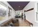 Inviting sunroom featuring tile flooring, natural light, and a stylish plum-colored ceiling at 5630 Winthrop Ave, Indianapolis, IN 46220