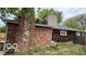 View of the side of a brick house with a stone chimney and green roof at 252 Ringwood Way, Anderson, IN 46013