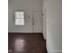 Bright living area with hardwood flooring, a large window for natural light, and a door leading to other rooms at 3619 N Hawthorne Ln, Indianapolis, IN 46218