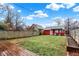 Wide view of the backyard with a detached garage, deck, green lawn, and privacy fence at 4616 Carrollton Ave, Indianapolis, IN 46205