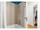 Tiled bathtub and shower with glass doorknob and door to the room's exit at 4616 Carrollton Ave, Indianapolis, IN 46205