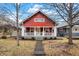 Inviting red house featuring a cozy front porch and landscaped front yard at 4616 Carrollton Ave, Indianapolis, IN 46205