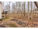 Backyard scene showing part of the house with a balcony and a dense woods behind a leaf-strewn lot at 9399 Irishmans Run Ln, Zionsville, IN 46077