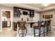 Basement bar with stone backsplash, brown cabinets and seating at 9399 Irishmans Run Ln, Zionsville, IN 46077