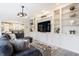 Bright living room featuring custom built-in shelving, a modern light fixture, and comfortable sectional seating at 9399 Irishmans Run Ln, Zionsville, IN 46077