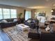 Inviting living room featuring hardwood floors, comfortable leather seating, and ample natural light from large windows at 19438 Astoria Ave, Sheridan, IN 46069