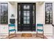 Front entrance with black door, two chairs, brick steps, and neighborhood sign at 2301 Nowland Ave, Indianapolis, IN 46201