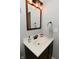 Small bathroom with dark brown vanity, white sink, and updated lighting at 6639 N College Ave, Indianapolis, IN 46220