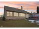 The backyard offers a gray deck, brick retaining wall, patio seating and green lawn during a colorful sunset at 10842 Belmont Cir, Indianapolis, IN 46280