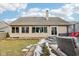 A home's backyard features a patio with wicker seating, a deck, and a lush lawn partially covered in snow at 10842 Belmont Cir, Indianapolis, IN 46280