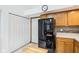 Kitchen with wood cabinets, black refrigerator, and white doors to pantry at 10842 Belmont Cir, Indianapolis, IN 46280