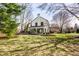 Spacious backyard with mature trees and lush lawn featuring a sunroom addition to the home at 128 Wellington Rd, Indianapolis, IN 46260
