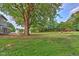 Sprawling backyard featuring a large tree, green grass, and access to the water at 1753 Skyline Dr, Greenwood, IN 46143
