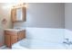 Bathtub and vanity in the bathroom, featuring a large mirror and a bathtub with white backsplash at 310 Green St, Plainfield, IN 46168
