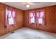 Bedroom with light carpet, wood paneled walls and two windows framed with pink curtains at 310 Green St, Plainfield, IN 46168
