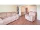 Spacious living room with hardwood floors leads to dining area, featuring a tan couch and a chair at 310 Green St, Plainfield, IN 46168