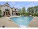 In-ground pool with brick home, dining table, lounging chairs, and a basketball hoop at 5030 Nightshade Ln, Noblesville, IN 46062